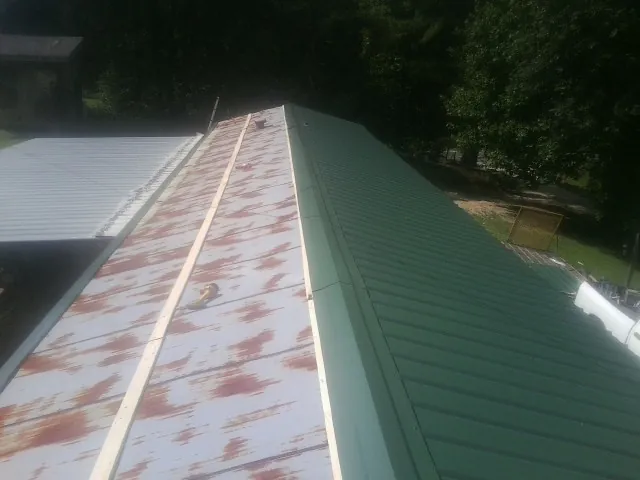 Old rusted panels beside newly installed green metal roofing — Wind Damage Roof Repair by Roofing Brothers in Woodburn