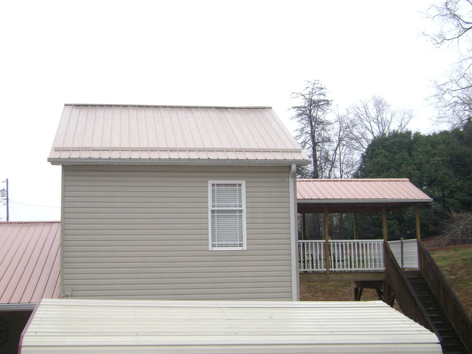 Tan metal roofs on a two story addition and attached porch, from a Roof Replacement job in Woodburn